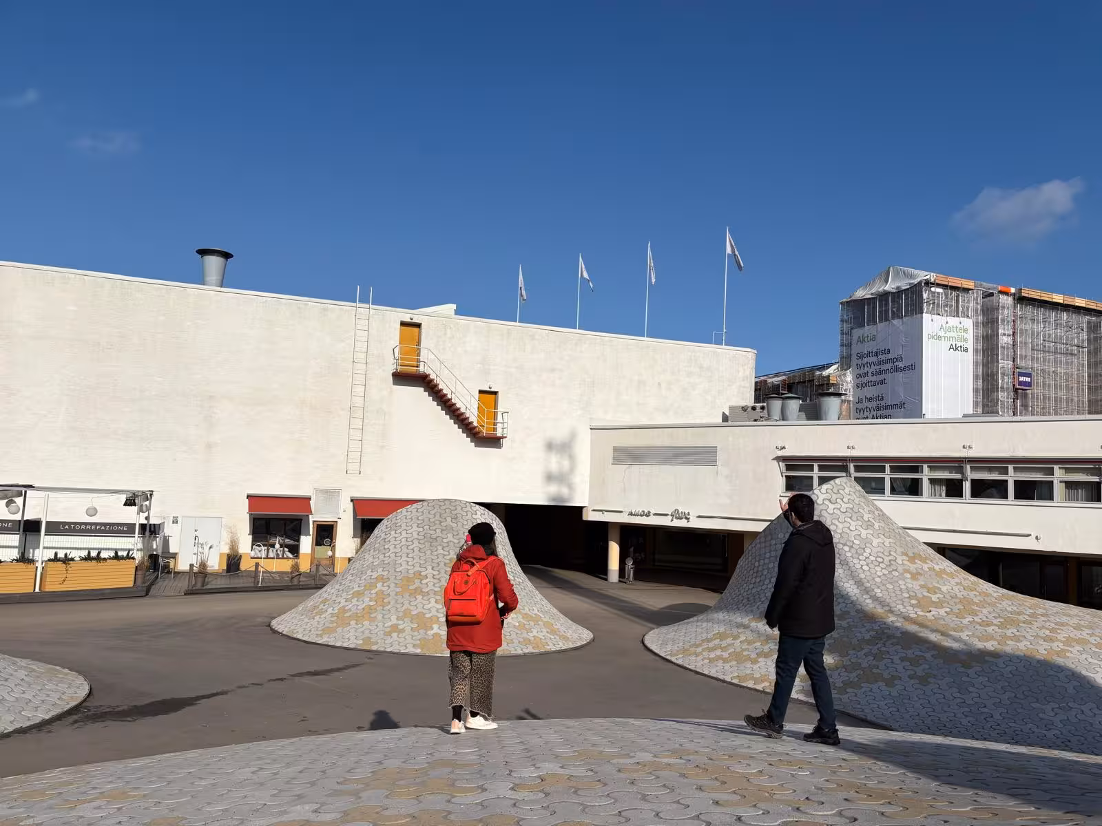 Modern architectural plaza with unique structures and visitors, offering a contemporary design tour experience.