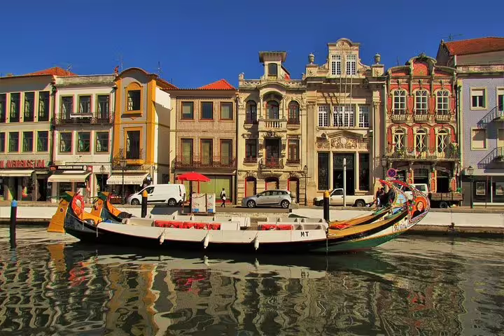 Traditional moliceiro boat on a sunny canal in Aveiro, Portugal, showcasing colorful architecture and vibrant culture.