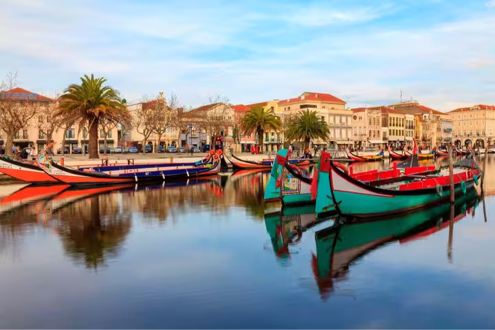 Colorful moliceiro boats reflected in the tranquil canals of Aveiro, highlighting the charm of this private Coimbra and Aveiro tour.