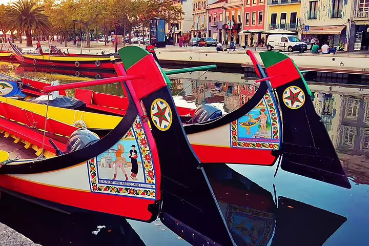 Traditional painted moliceiro boats in Aveiro's canal, showcasing the cultural allure of a full-day Costa Nova excursion.