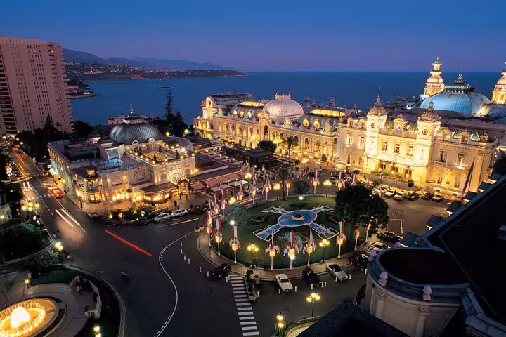 Stunning aerial view of Monaco's Casino Square illuminated at night, showcasing luxury architecture and vibrant nightlife.