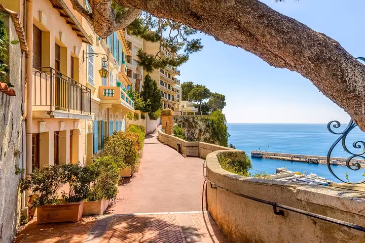 Scenic coastal pathway in Monaco with yellow buildings, lush greenery, and Mediterranean Sea views