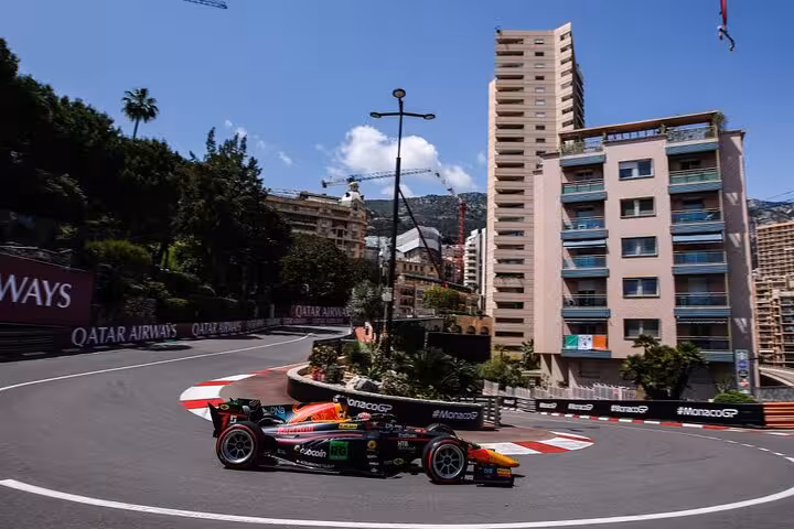 Formula racing car navigating tight street circuit at Monaco Grand Prix with Qatar Airways banners