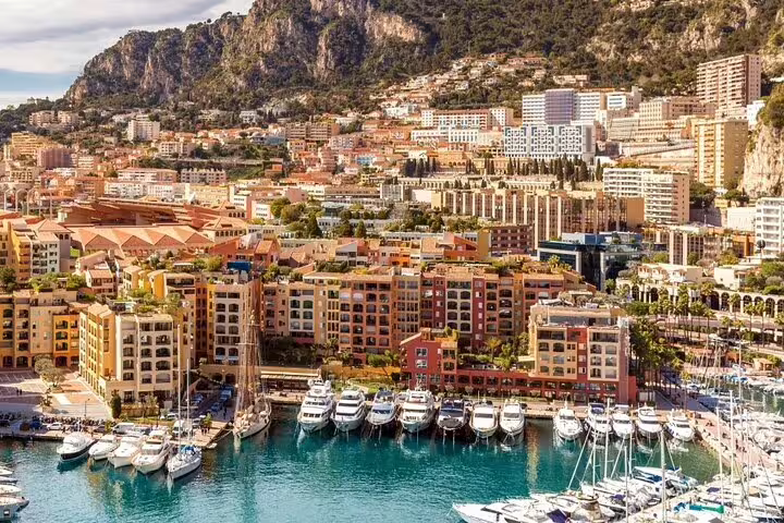 Monaco harbor with luxury yachts, colorful waterfront buildings, and mountain backdrop on the French Riviera