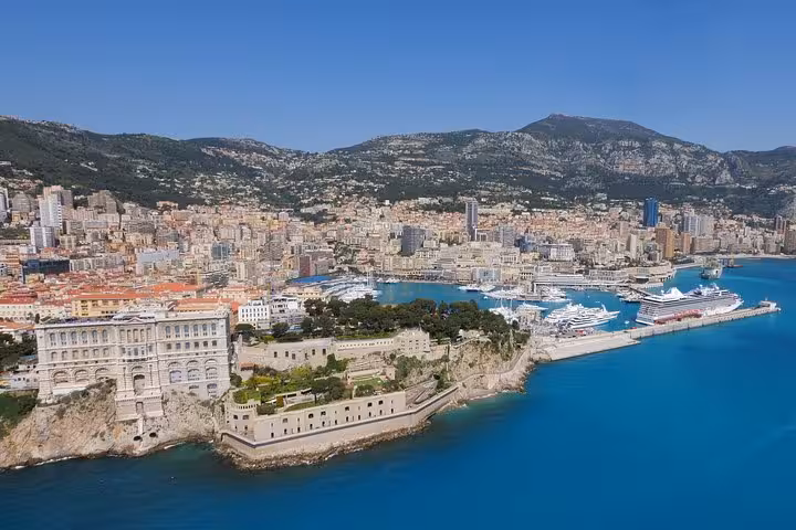 Aerial view of Monaco harbor with cruise ships, the Oceanographic Museum on rocky cliff, and Monte-Carlo cityscape