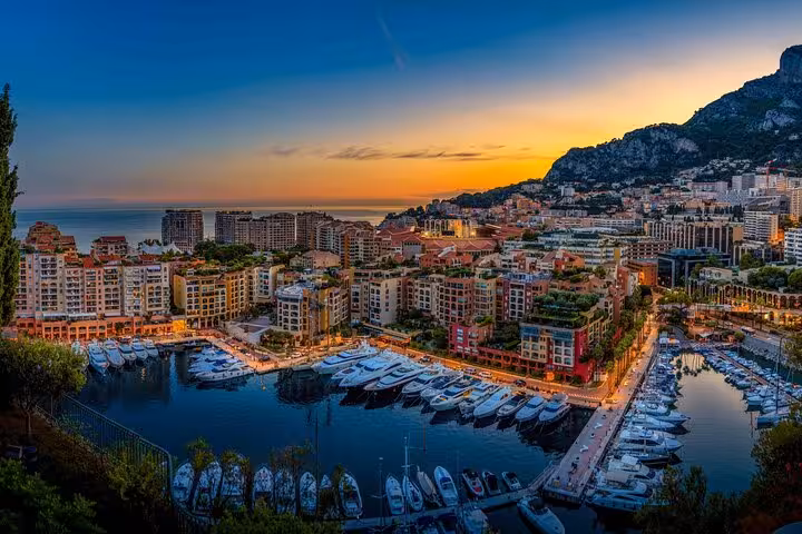 Panoramic sunset view of Monaco harbor with luxury yachts and colorful waterfront buildings along the French Riviera