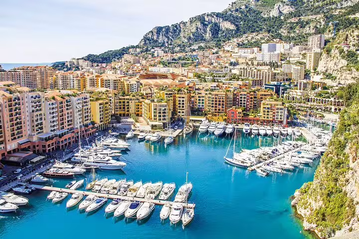 Colorful Monaco harbor with luxury yachts, vibrant waterfront buildings, and rocky hillside on the French Riviera