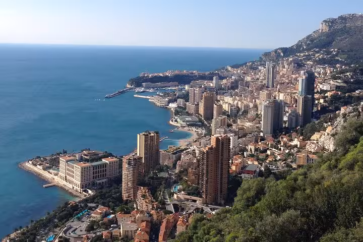 Aerial view of Monaco coastline with dense cityscape, luxury buildings, and Monte-Carlo harbor along the Mediterranean Sea