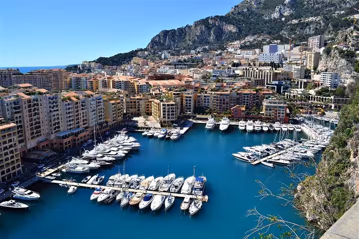 Aerial view of Monaco's Port de Fontvieille marina with luxury yachts, colorful buildings, and mountain backdrop