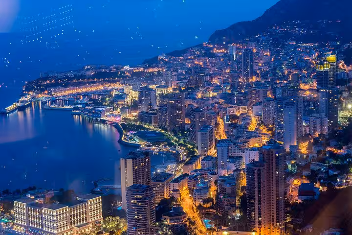 Stunning aerial view of Monaco and Monte-Carlo illuminated at night, showcasing vibrant city lights and coastal beauty.