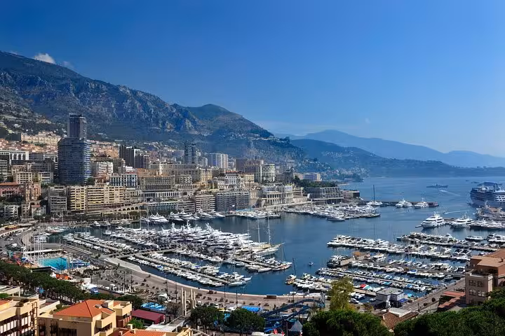 Aerial view of Monaco's Port Hercule marina packed with yachts, Monte Carlo cityscape and mountains behind