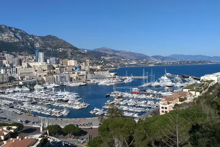 Aerial view of Monaco's Port Hercules marina filled with luxury yachts, city buildings, and Mediterranean coastline