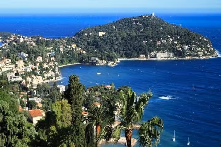 Aerial view of Monaco coastline with blue Mediterranean Sea, lush hillside villas, and Cap Ferrat peninsula