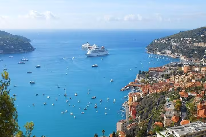 Aerial view of Villefranche-sur-Mer bay with cruise ships, sailboats, and Monaco coastal town