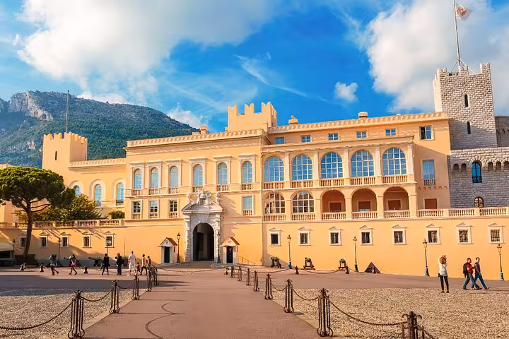 Prince's Palace of Monaco courtyard with yellow facade, arched windows, and tourists on sunny day