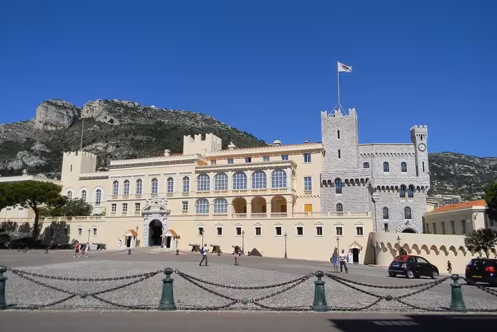 Prince's Palace of Monaco with grey stone towers and cream facade set against rocky mountain backdrop