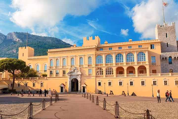 Prince's Palace of Monaco courtyard with yellow facade, battlements, and visitors on sunny day
