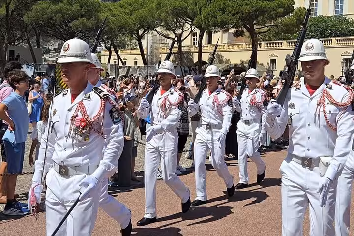Monaco Palace Guard changing ceremony in white uniforms marching before a crowd of tourists