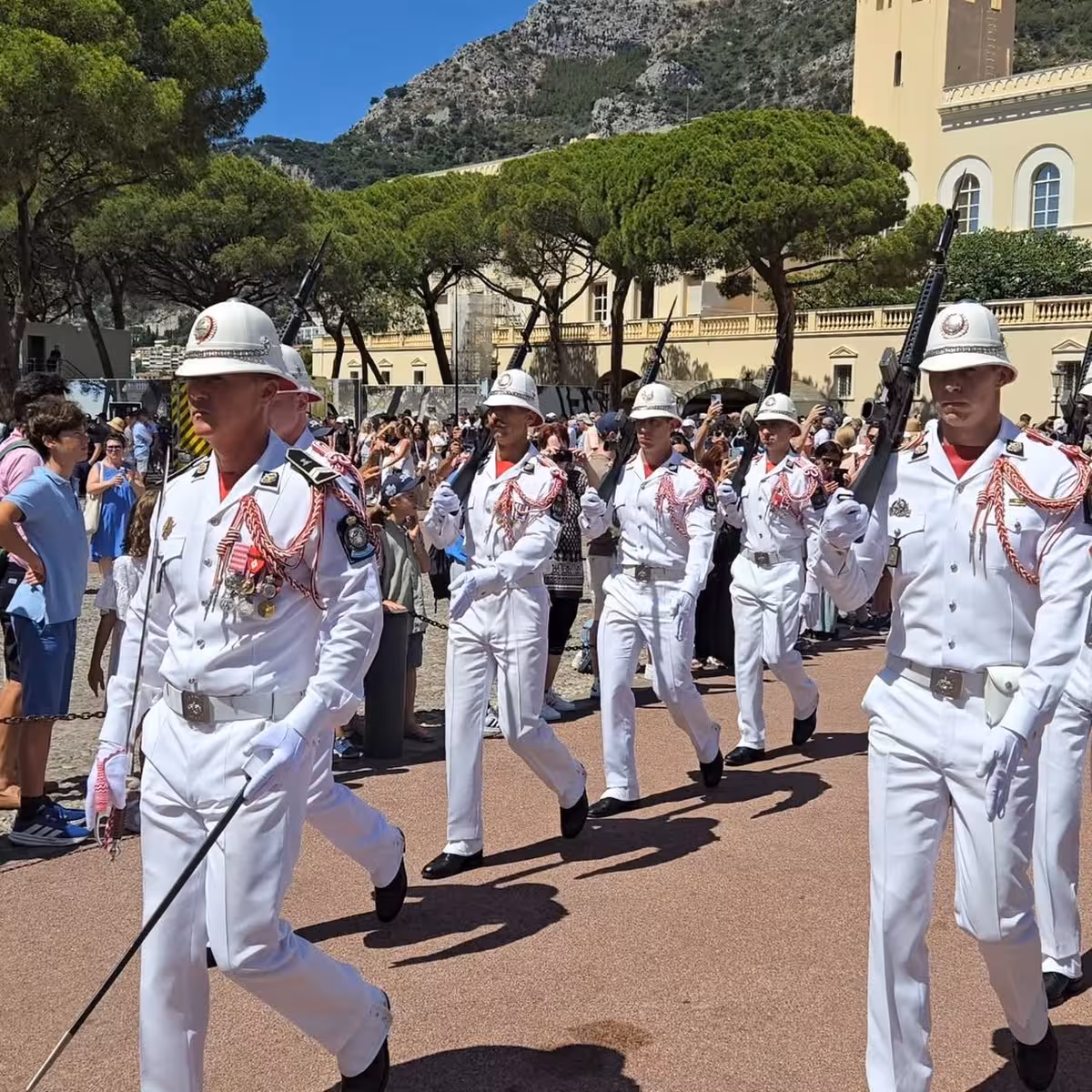Monaco Palace Guard changing ceremony in white uniforms marching before crowds of tourists