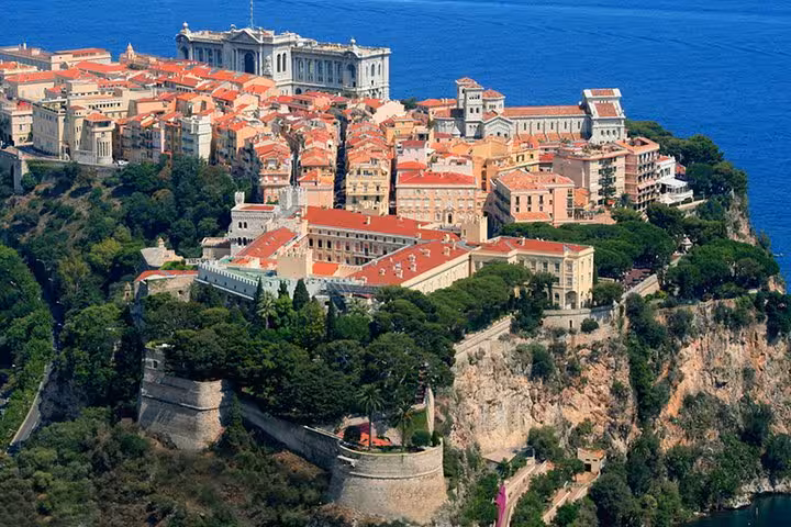 Aerial view of Monaco's historic Rock district with orange-roofed buildings perched on cliffs above the Mediterranean Sea