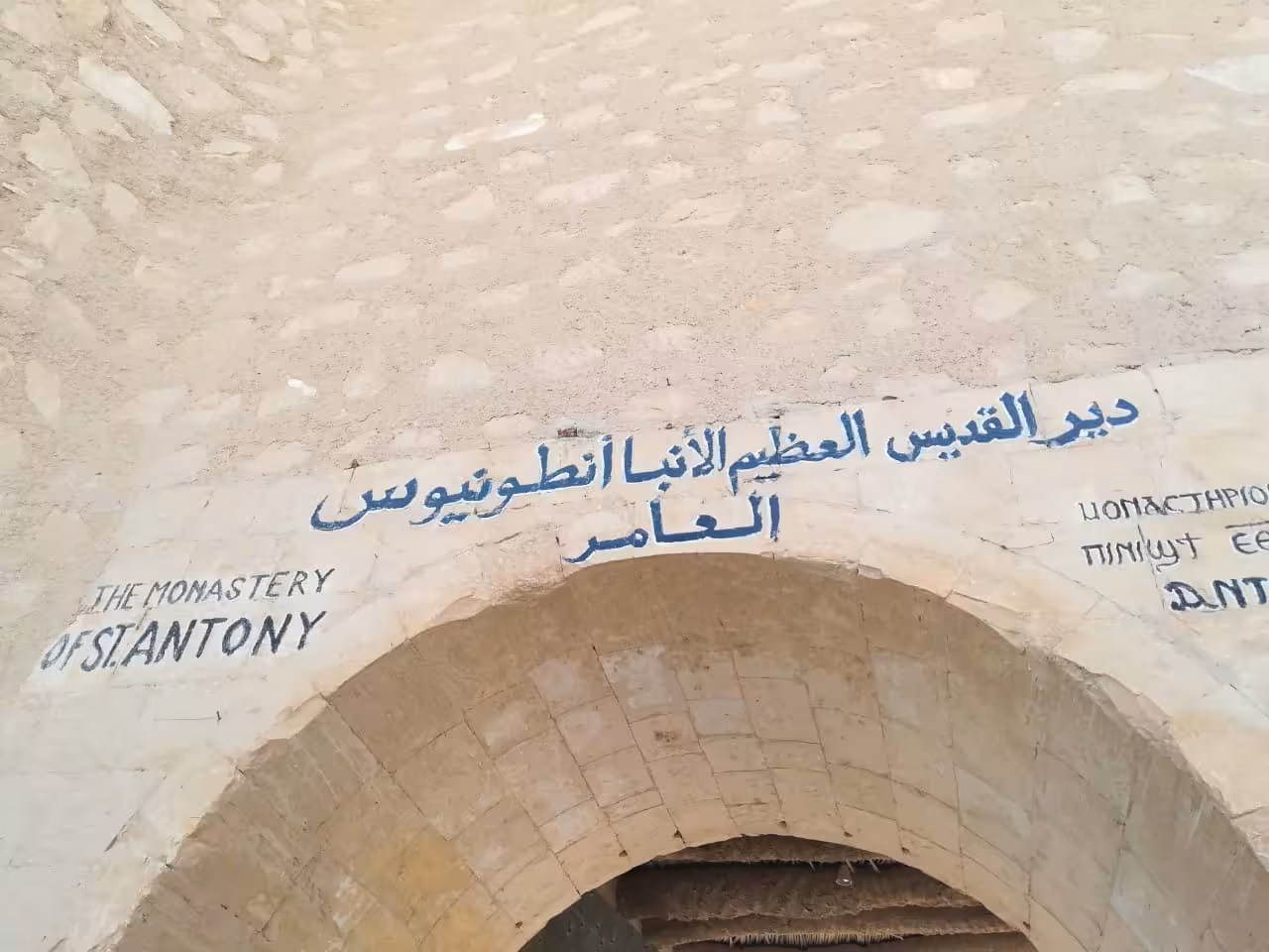Stone archway entrance of the Monastery of St. Antony with Arabic, English, and Coptic inscriptions