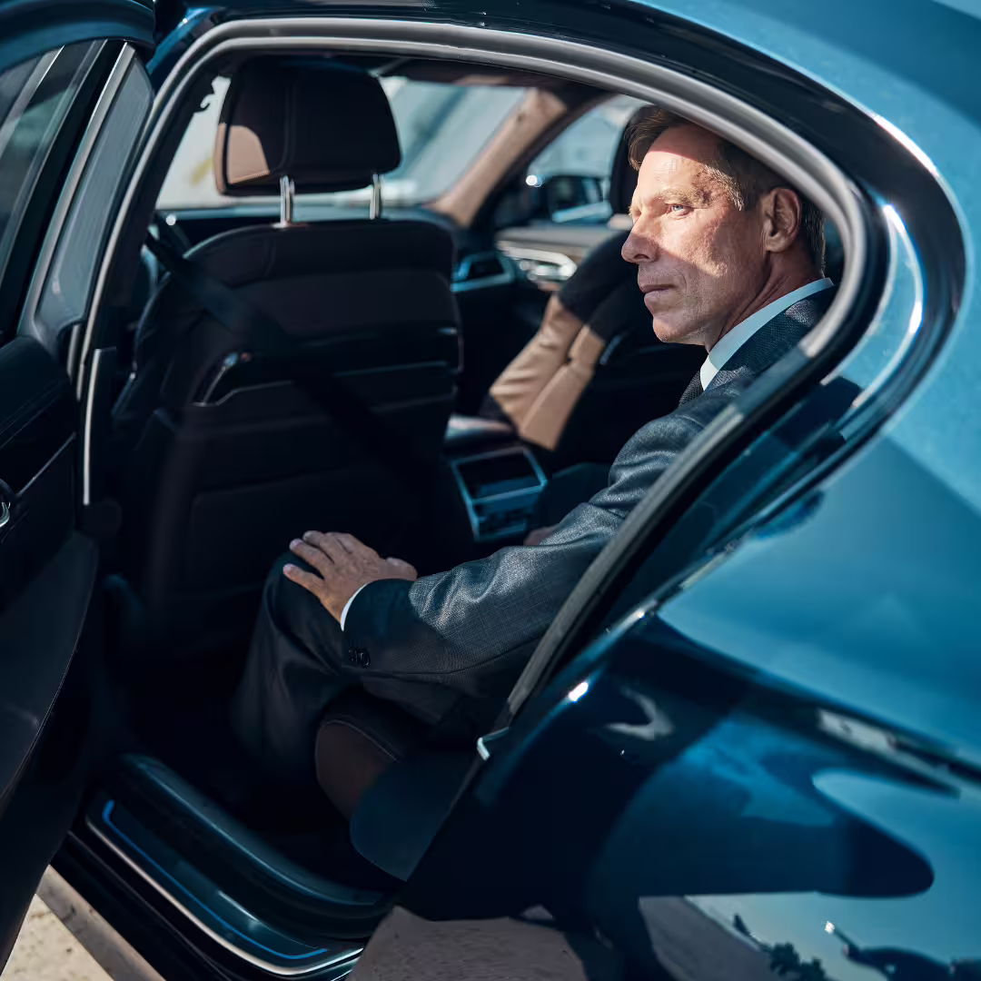 Business traveler relaxing in back seat of premium sedan during Mondello Palace Hotel to Palermo airport PMO private transfer