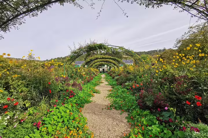 Flower-lined path under vine arches in Monet’s Garden, Giverny, on a private Auvers-sur-Oise day tour