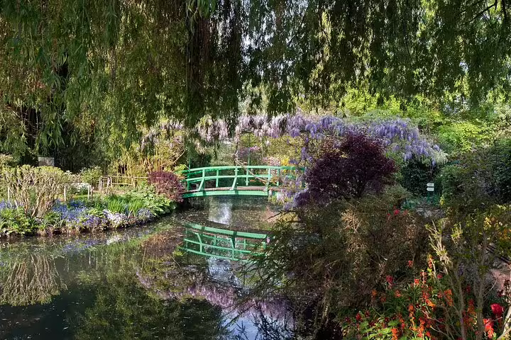Green Japanese bridge over lily pond with wisteria blooms at Monet's Garden in Giverny, France