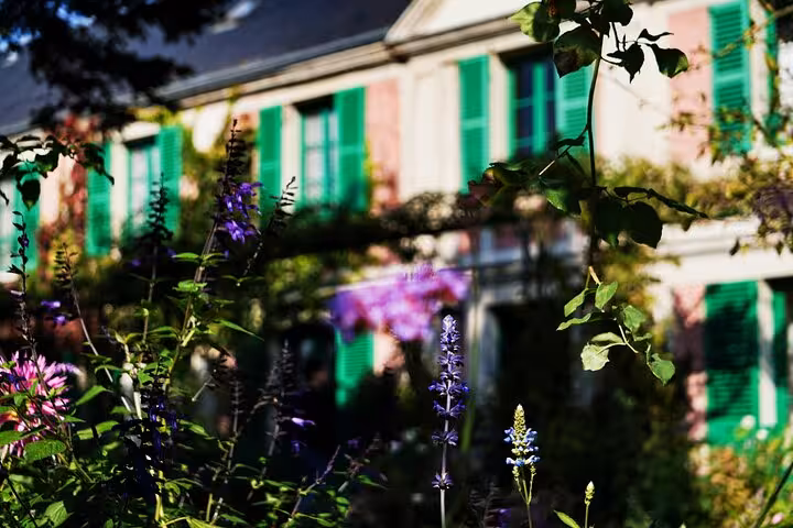 Colorful wildflowers in front of Monet's pink house with green shutters in Giverny gardens