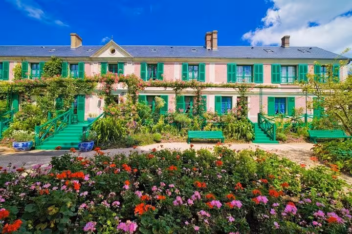 Claude Monet's pink house with green shutters and colorful flower garden in Giverny, France
