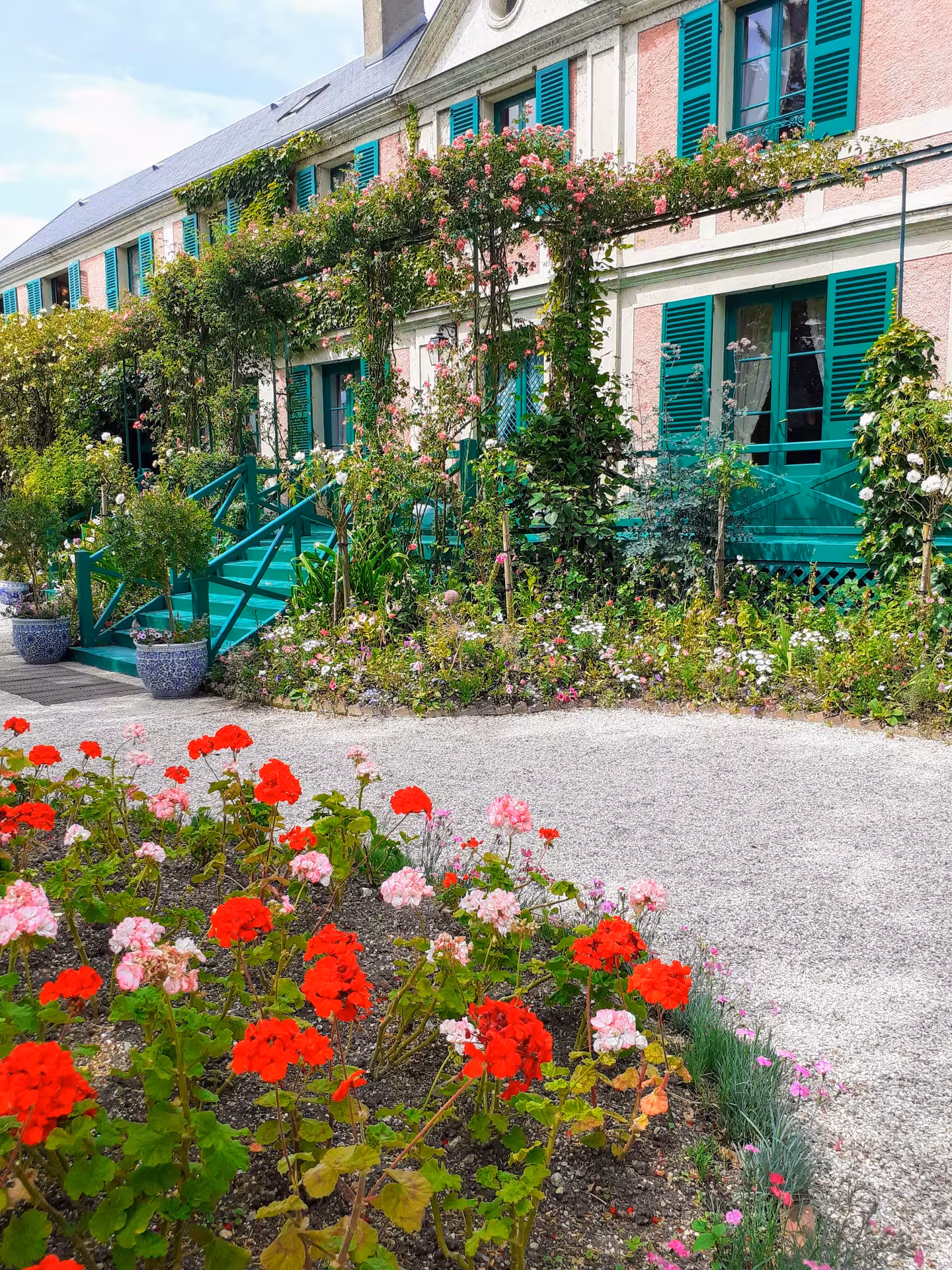 Claude Monet's pink house with teal green shutters and colorful flower garden in Giverny, France