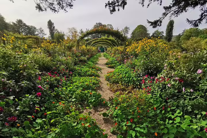 Flower-lined path and rose arches in Monet’s Garden, Giverny, on a private tour from Paris to Auvers-sur-Oise