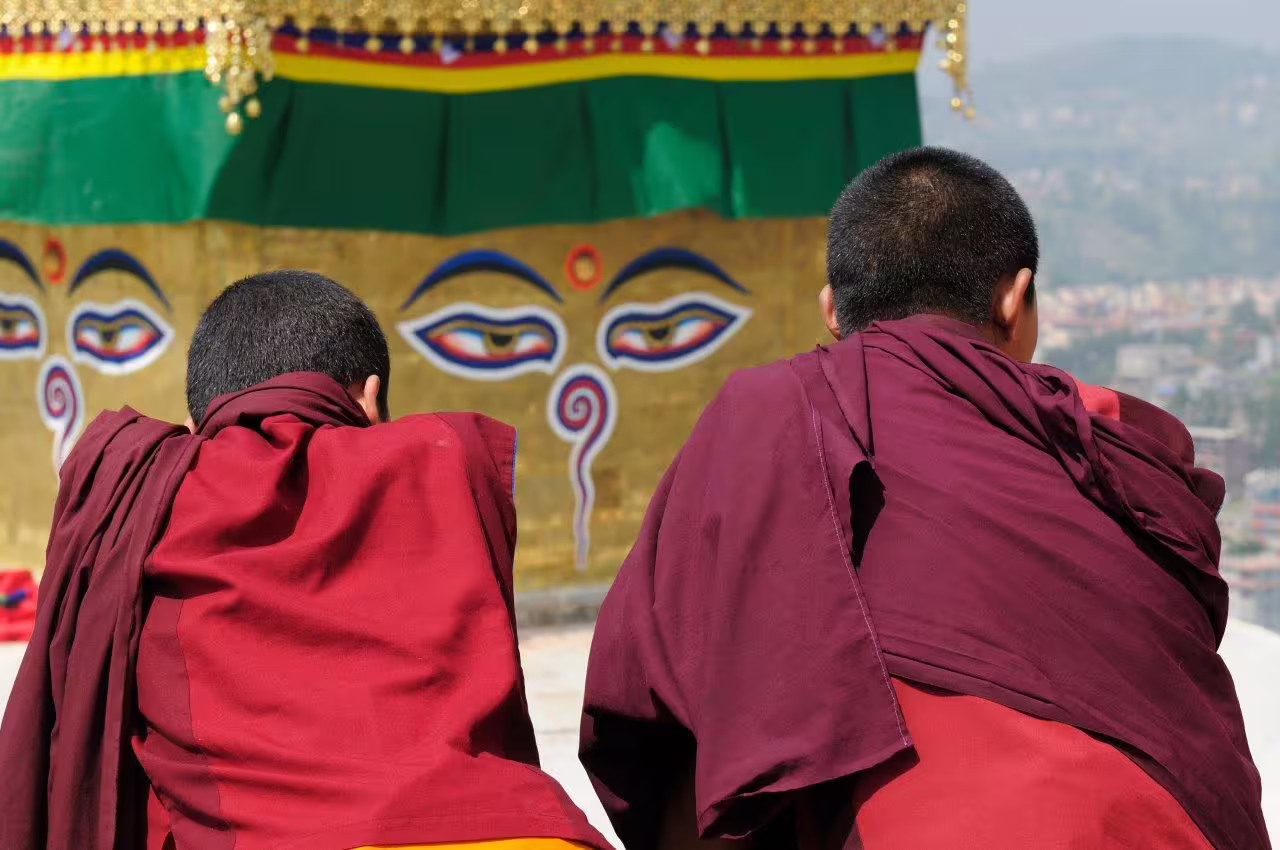 Two monks in traditional robes at Swayambhunath Stupa in Kathmandu, capturing spiritual essence on the Golden Triangle tour.