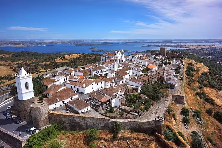 Aerial view of the historic village of Monsaraz with whitewashed houses and Alqueva Lake in the background, perfect for a private walking tour.