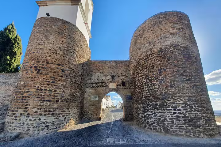 Historic stone gate at Monsaraz under a clear blue sky, featured in the From Lisboa: Evora & Monsaraz Private Full-Day Tour.