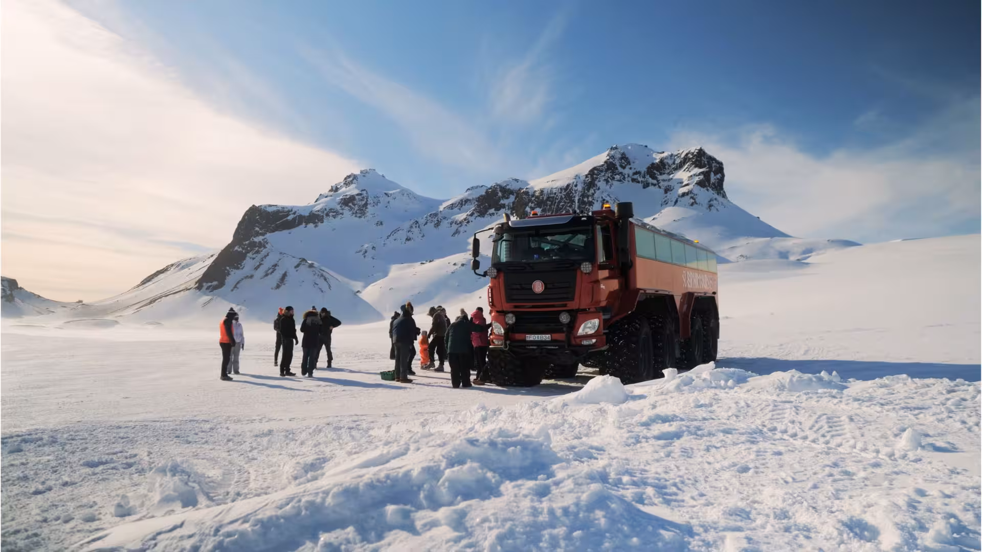 Red Monster truck on glacier with guests enjoying the view