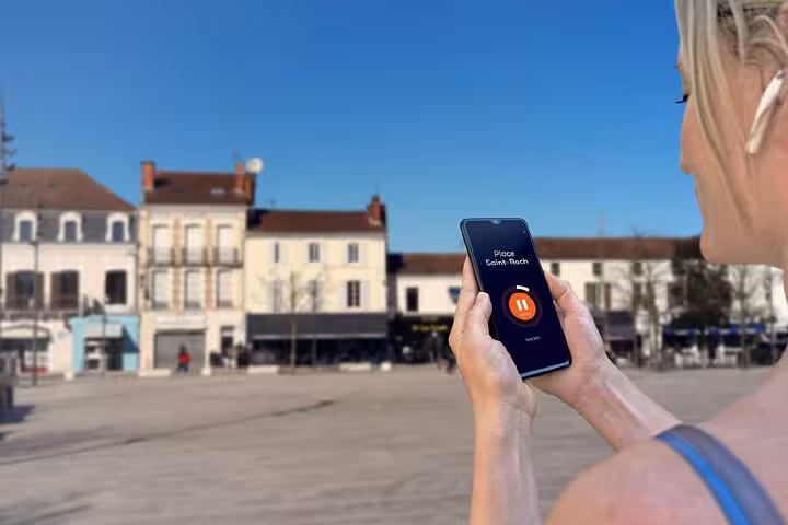 Woman holding smartphone with audio guide app at Place Saint-Roch square in Mont de Marsan