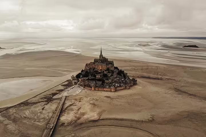 Aerial view of Mont Saint Michel abbey rising from tidal flats in Normandy, France at low tide