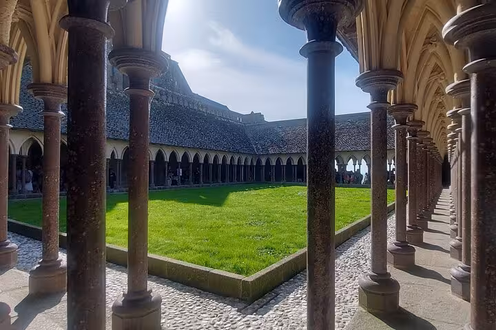 Mont Saint Michel Abbey cloister courtyard with stone columns, a highlight on small group day trip by luxury van