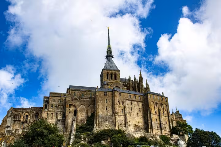 Mont-Saint-Michel abbey rising on rocky island against blue sky, Normandy France