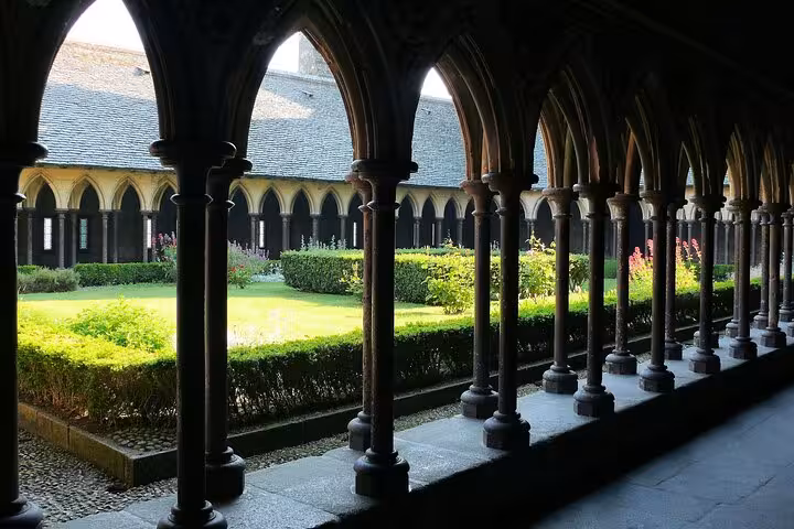 Gothic cloister arches and garden at Mont Saint Michel Abbey, a highlight on small group day trip by luxury van