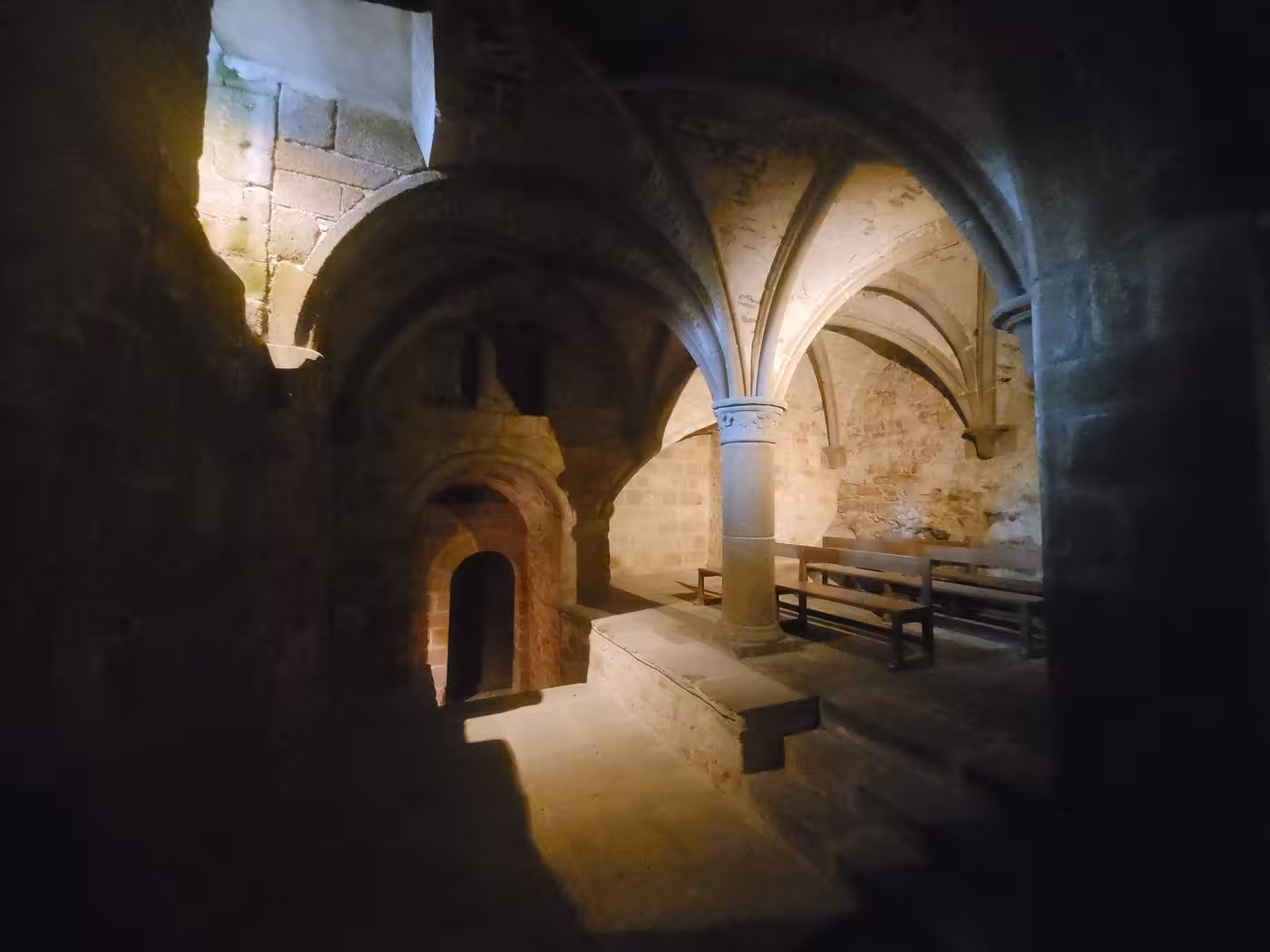 Medieval stone crypt with vaulted ceilings and arched doorway inside Mont-Saint-Michel abbey