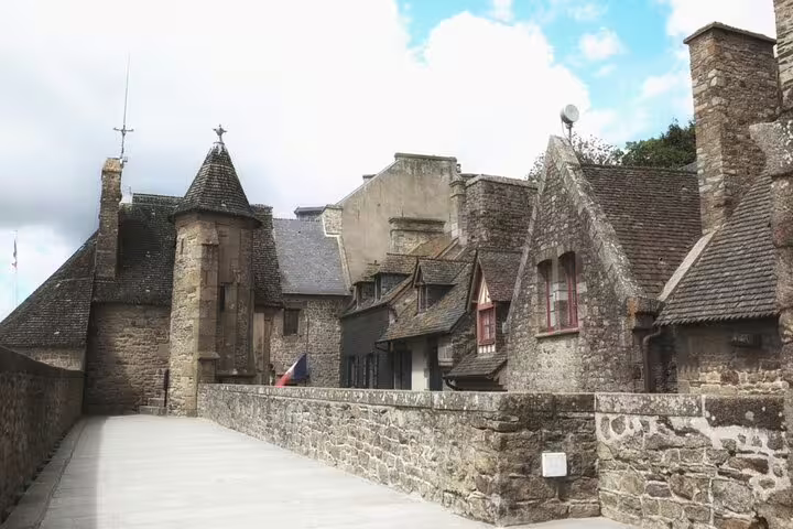 Medieval stone buildings and rampart walkway at Mont Saint-Michel with French flag