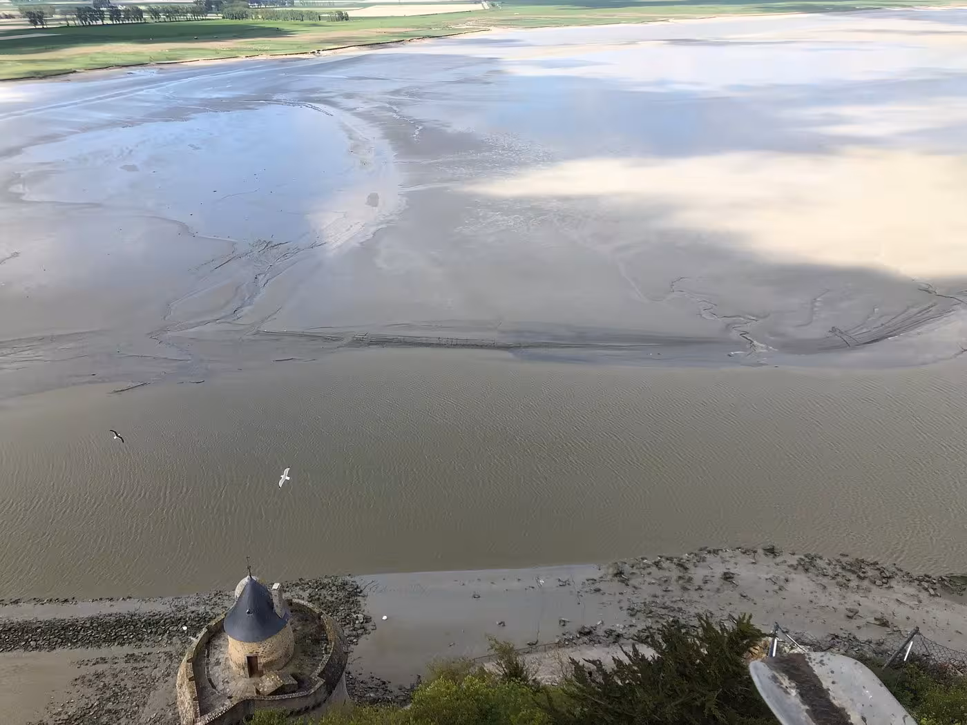 Aerial view of Mont-Saint-Michel tidal flats with medieval tower and muddy bay at low tide
