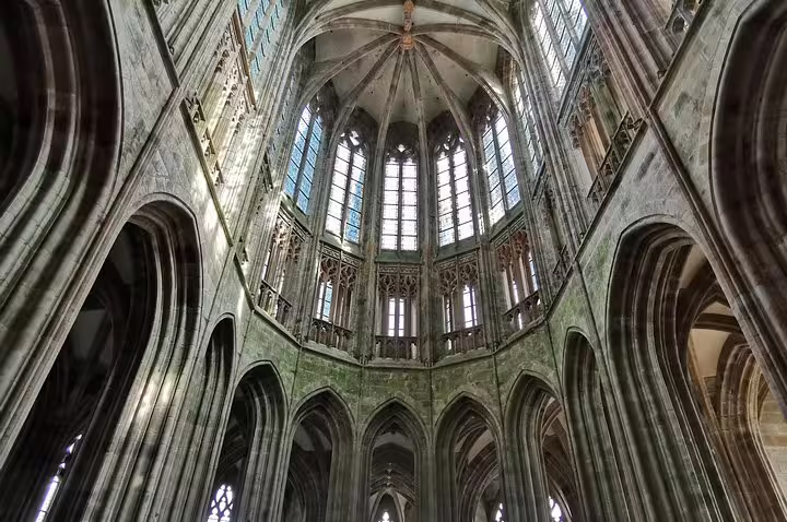 Gothic abbey interior at Mont St-Michel, soaring arches and stained glass on private guided day tour