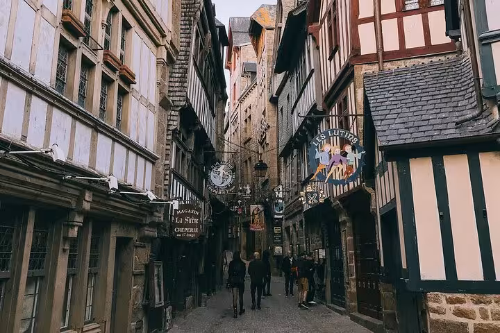 Medieval half-timbered street with shops and pedestrians at Mont-Saint-Michel, Normandy, France