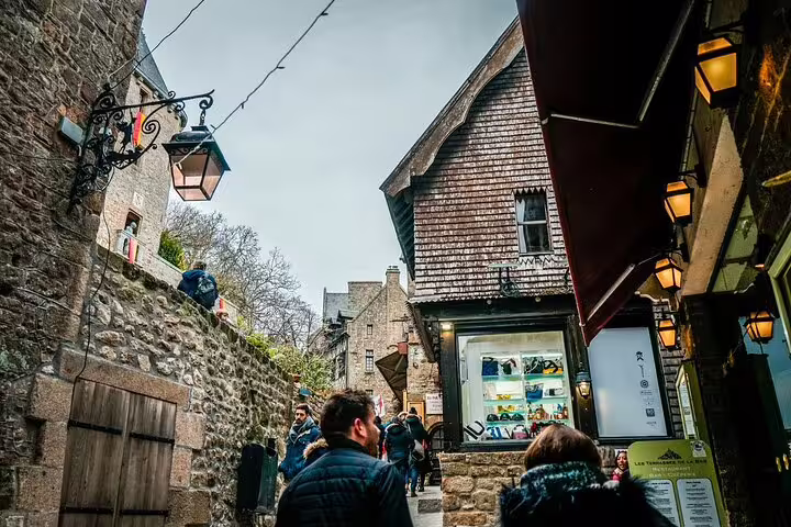Narrow medieval street with stone buildings and shops at Mont Saint Michel, France