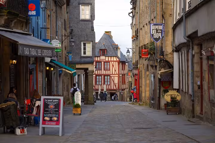 Historic Mont Saint Michel village street with shops and half-timbered house, small group luxury van day tour