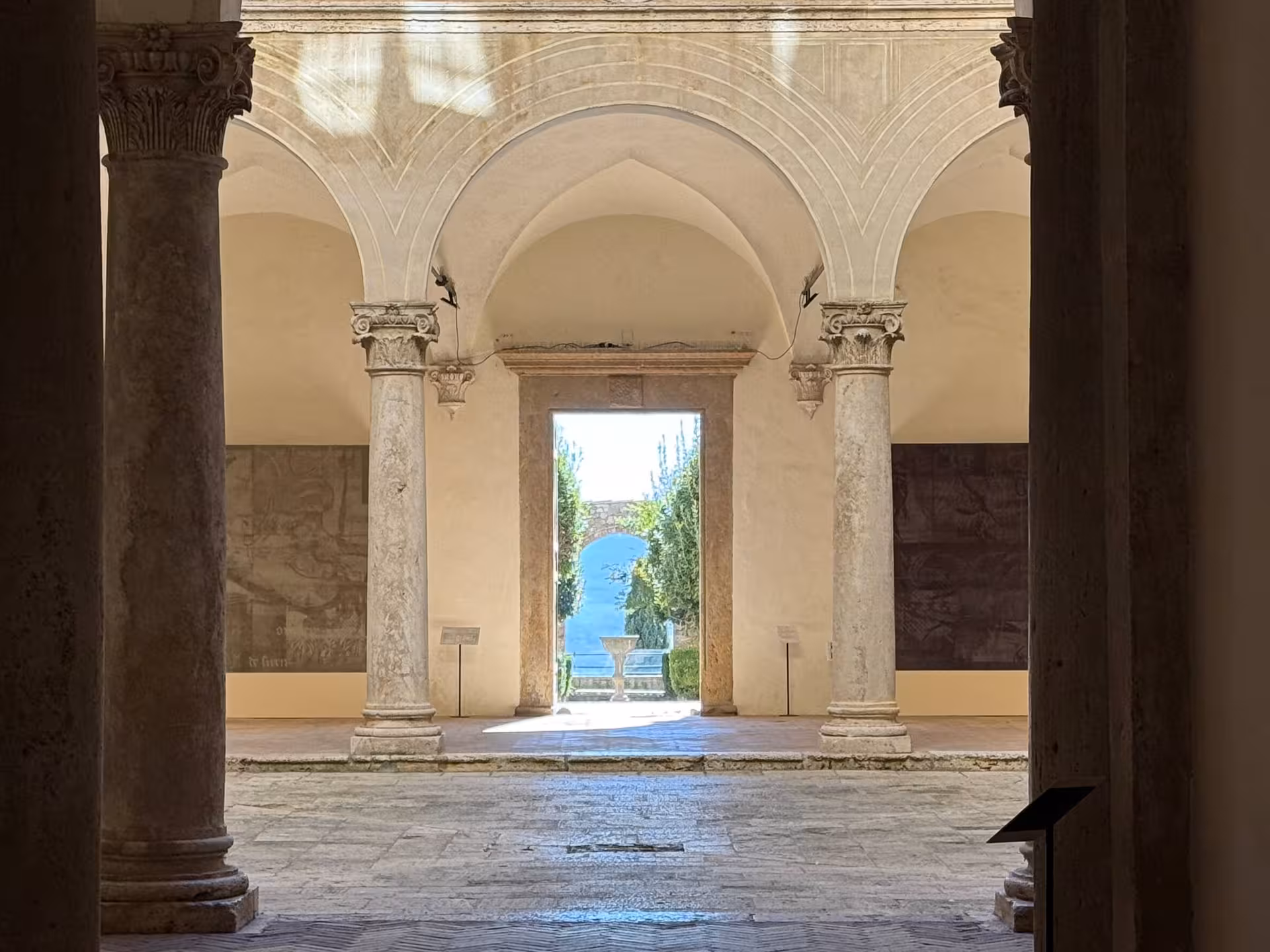 Elegant archway and columns in a historic Montalcino courtyard with views of the garden beyond.
