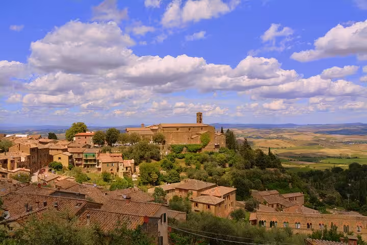 Stunning panoramic view of Montalcino's rolling hills and historic buildings under a vibrant blue sky, ideal for wine tours.